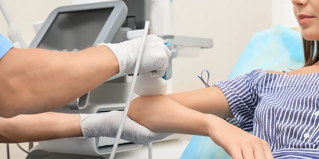 Dame undersøkes i armen ved hjelp av ultralyd.