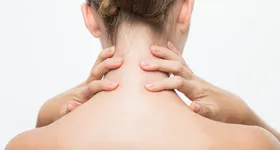 Kvinne med smerter, holder på nakken.